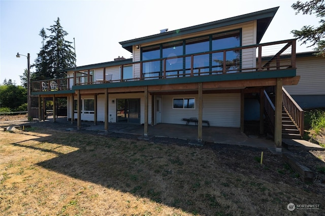 rear view of property with a wooden deck, a lawn, stairs, and a patio area