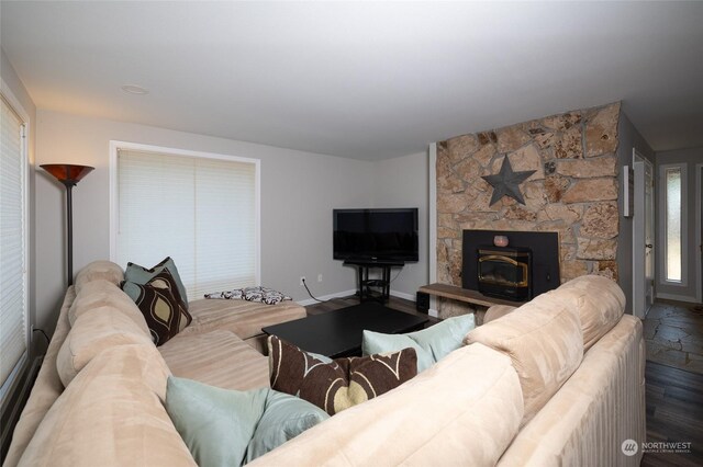 living room with a stone fireplace, baseboards, and wood finished floors