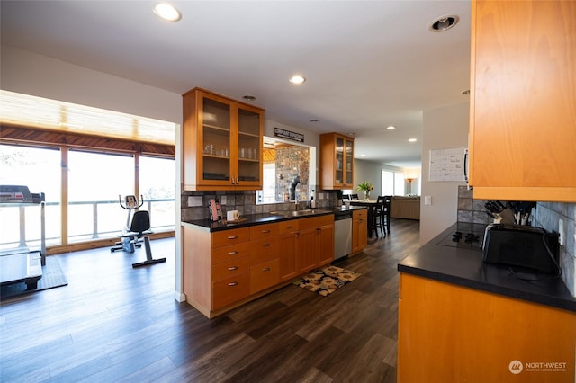 kitchen featuring decorative backsplash, dark wood-style floors, dark countertops, and stainless steel dishwasher