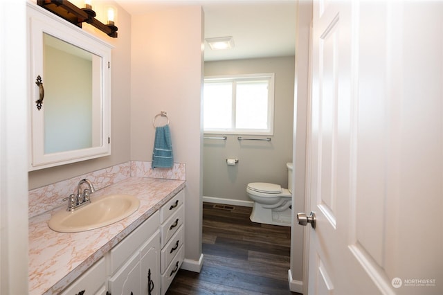 bathroom featuring toilet, vanity, baseboards, and wood finished floors