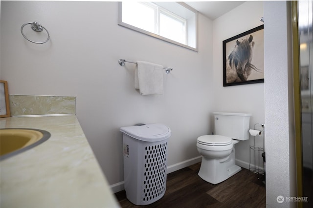 bathroom with toilet, wood finished floors, and baseboards
