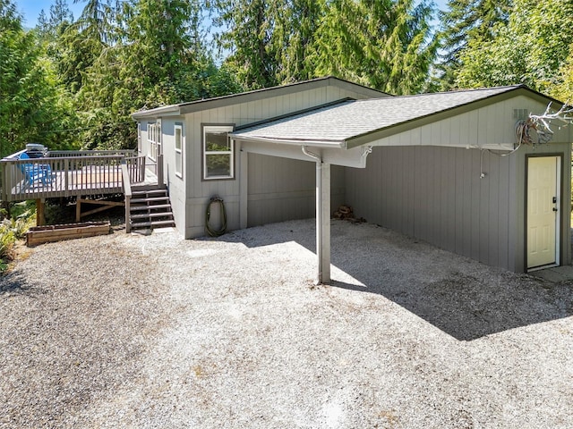 view of side of home with roof with shingles and a deck