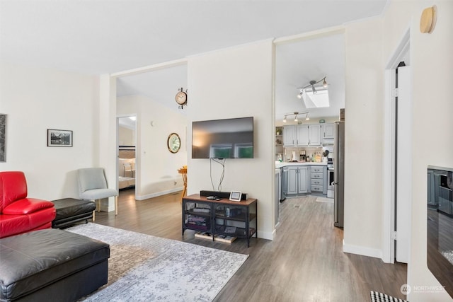 living area with track lighting, baseboards, and wood finished floors