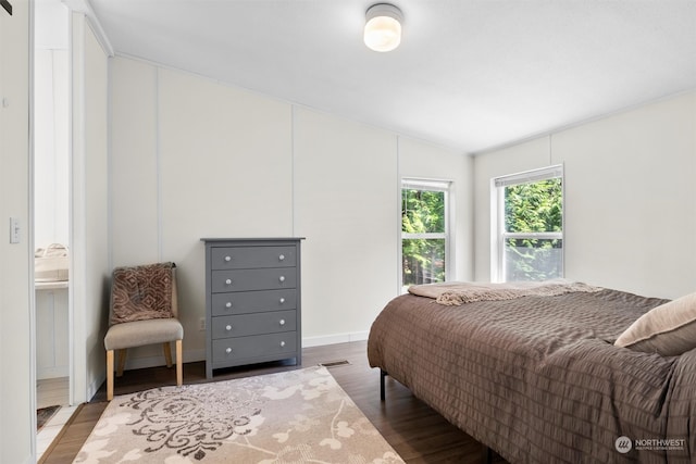 bedroom featuring hardwood / wood-style flooring, ensuite bathroom, and lofted ceiling