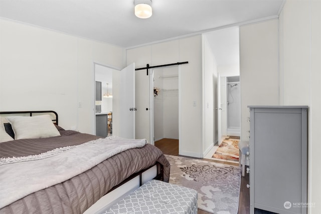 bedroom with a walk in closet, a closet, light wood-type flooring, and a barn door