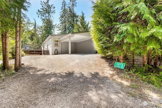 exterior space featuring gravel driveway, a deck, and an attached carport