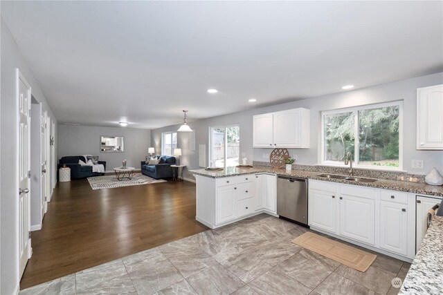 kitchen featuring stone countertops, a sink, white cabinetry, open floor plan, and stainless steel dishwasher