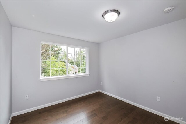 empty room with dark wood-style floors and baseboards