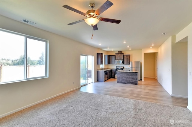 kitchen featuring sink, light carpet, a kitchen island, ceiling fan, and stainless steel appliances