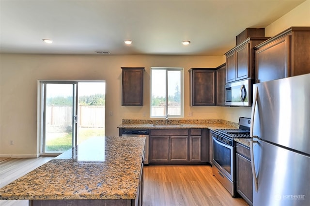 kitchen featuring appliances with stainless steel finishes, light stone countertops, sink, and a kitchen island