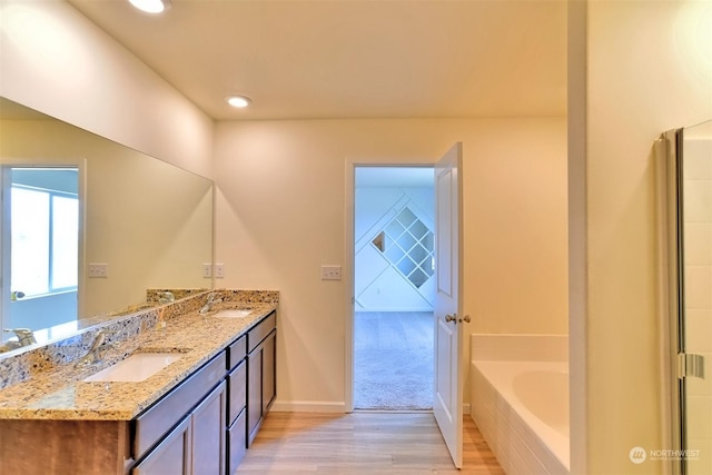 bathroom featuring vanity, hardwood / wood-style floors, and a tub