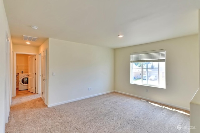 empty room featuring light carpet and washer / clothes dryer