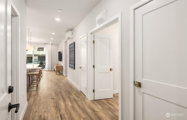 hall featuring a wall unit AC and light wood-type flooring