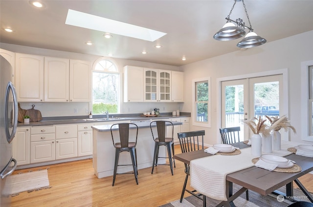 kitchen with a skylight, white cabinetry, light hardwood / wood-style flooring, and a kitchen island