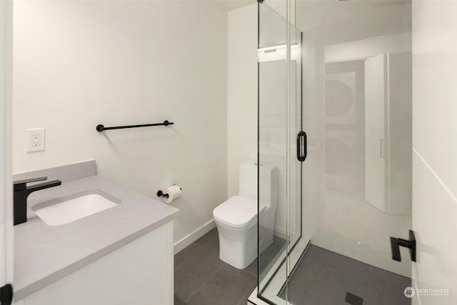 bathroom with tile patterned flooring, vanity, a shower with shower door, and toilet