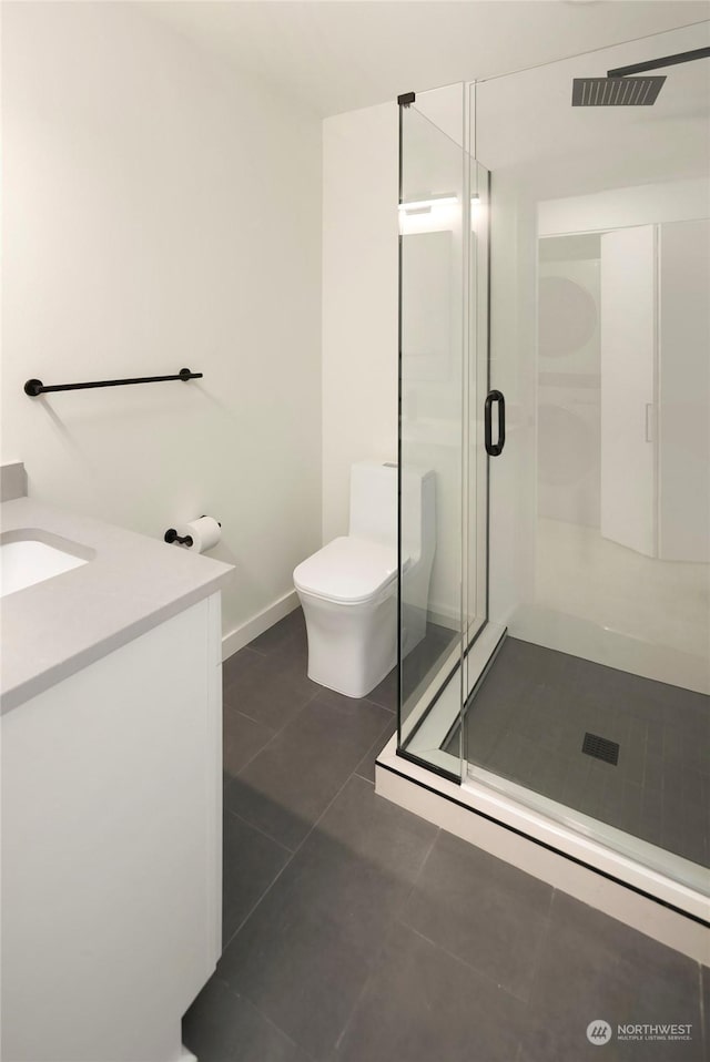 bathroom featuring a shower with door, vanity, tile patterned floors, and toilet