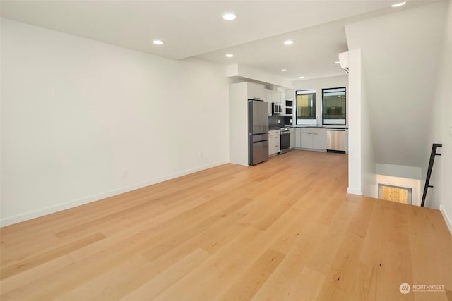 kitchen with appliances with stainless steel finishes, sink, white cabinets, and light hardwood / wood-style floors