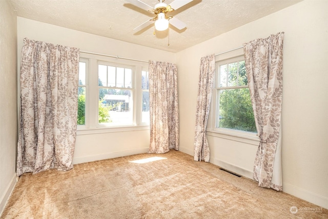 carpeted empty room with ceiling fan and a textured ceiling