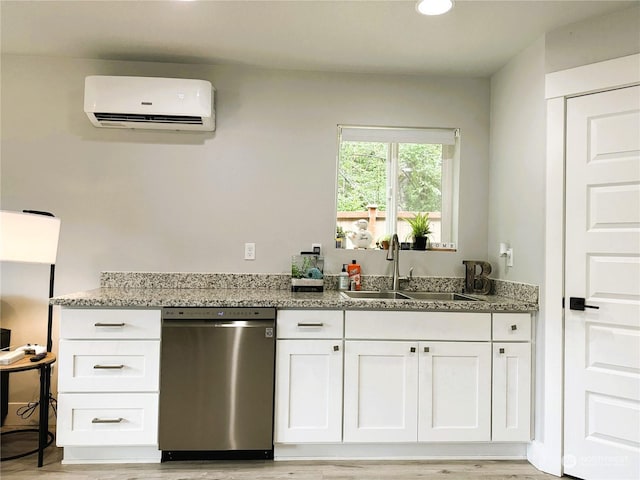 kitchen with a wall mounted AC, sink, stainless steel dishwasher, and white cabinets