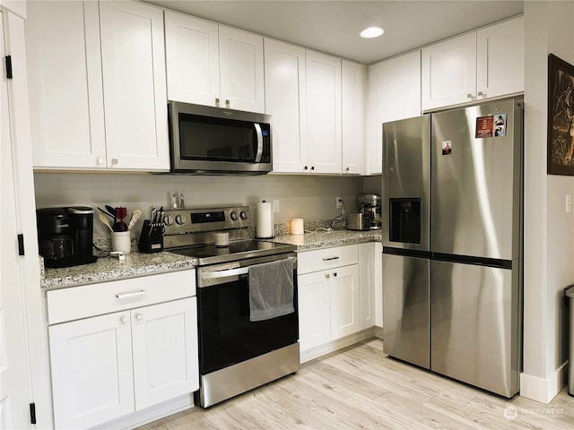 kitchen with white cabinetry, light stone counters, and appliances with stainless steel finishes