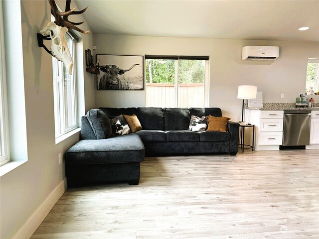 living room with a wall mounted AC and light hardwood / wood-style flooring