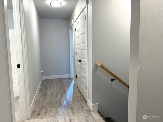 hallway featuring light hardwood / wood-style floors and a textured ceiling