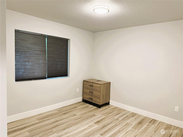 unfurnished room featuring a textured ceiling and light wood-type flooring