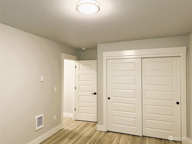 unfurnished bedroom featuring light hardwood / wood-style flooring, a closet, and a textured ceiling