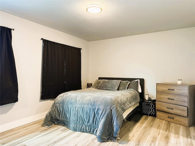 bedroom with light hardwood / wood-style flooring and a textured ceiling