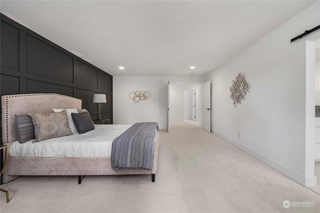 bedroom featuring light carpet and a barn door