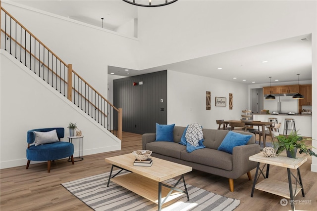 living room featuring a towering ceiling and light hardwood / wood-style flooring