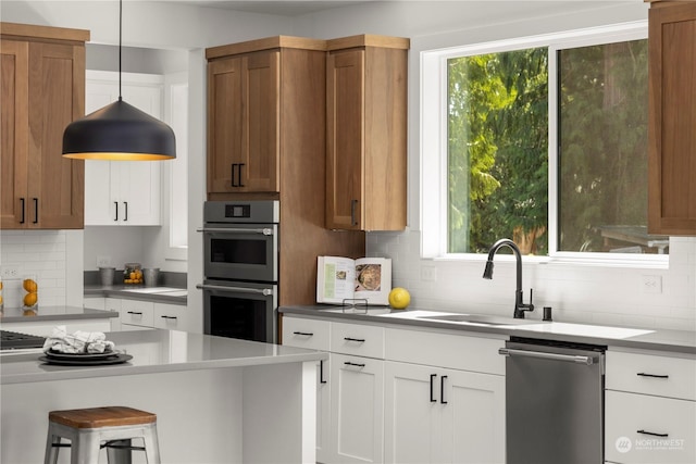 kitchen with sink, white cabinets, hanging light fixtures, stainless steel appliances, and plenty of natural light