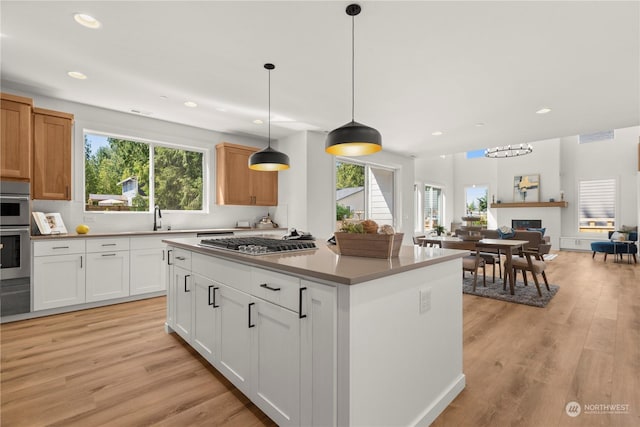 kitchen with appliances with stainless steel finishes, a center island, hanging light fixtures, and white cabinets