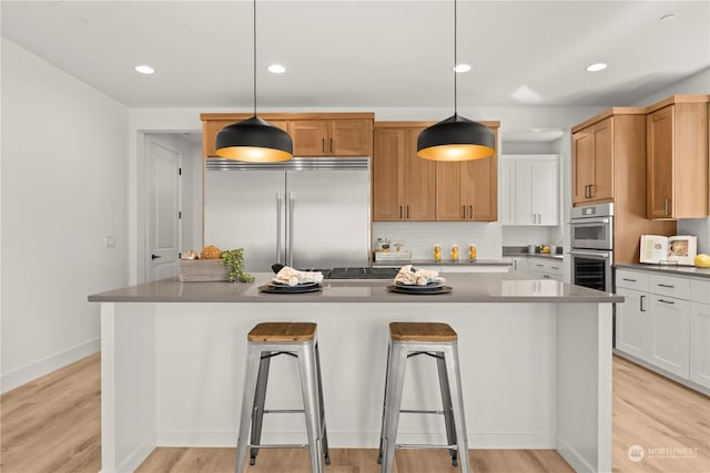 kitchen with decorative light fixtures, a breakfast bar area, white cabinets, and appliances with stainless steel finishes