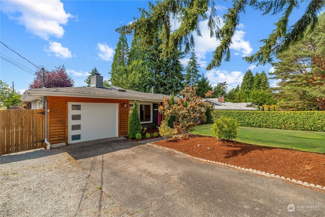 ranch-style home featuring a chimney, an attached garage, a front yard, fence, and driveway