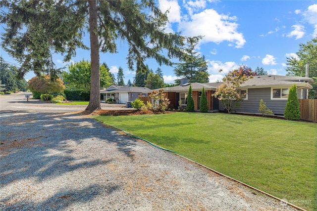 ranch-style house with driveway, a front lawn, and fence