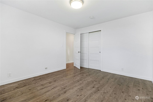 unfurnished bedroom with dark wood-type flooring and a closet