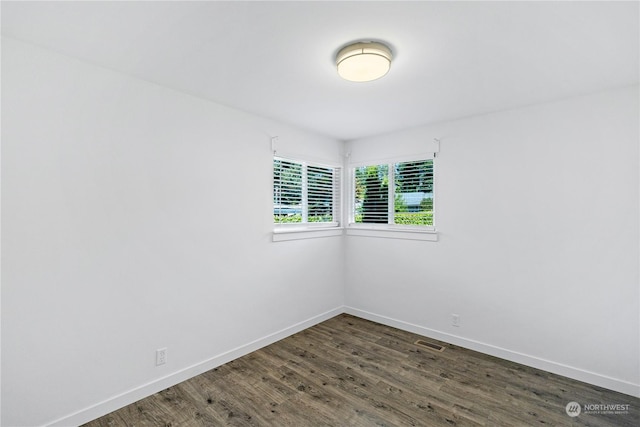 empty room featuring wood finished floors, visible vents, and baseboards