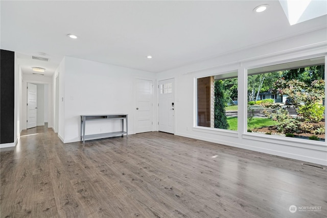 unfurnished living room with baseboards, wood finished floors, visible vents, and recessed lighting