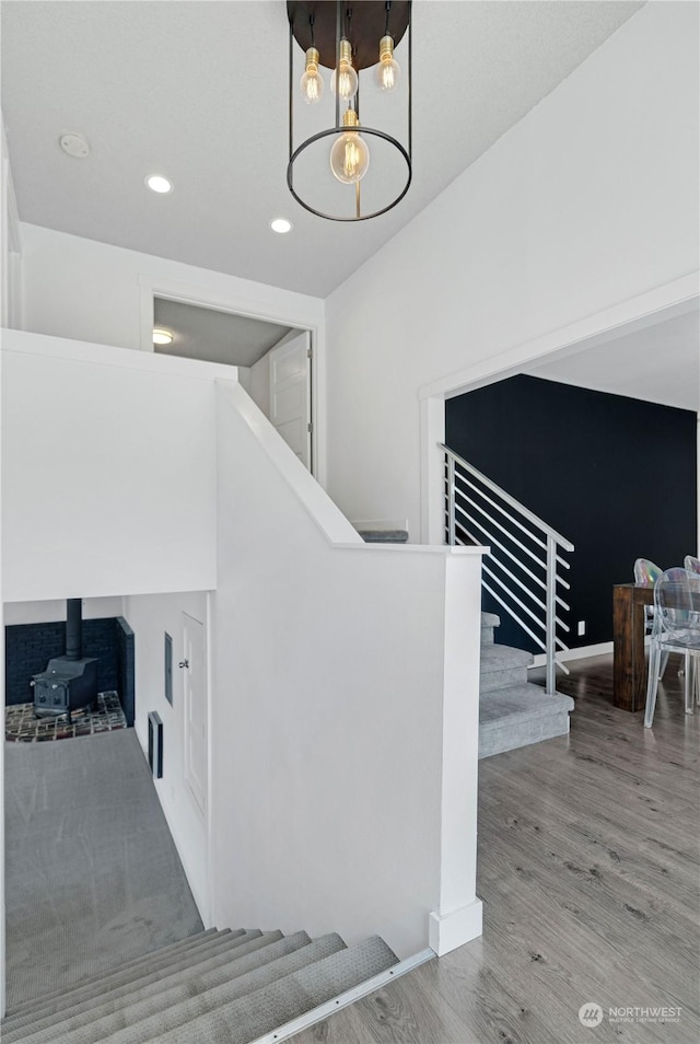 staircase with recessed lighting, an inviting chandelier, and wood finished floors