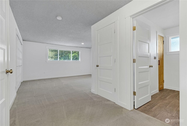 corridor with baseboards, a textured ceiling, and carpet flooring