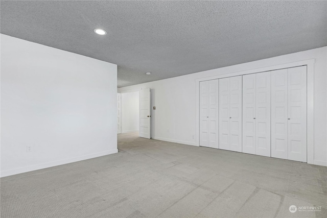 unfurnished bedroom with a textured ceiling, recessed lighting, carpet flooring, baseboards, and a closet