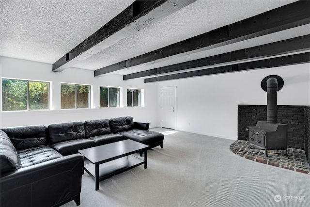 living room featuring a textured ceiling, a wood stove, beamed ceiling, and carpet