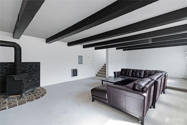 living area featuring carpet floors, stairs, beam ceiling, electric panel, and a wood stove