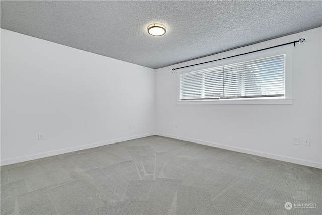 unfurnished room with a textured ceiling, carpet, and baseboards