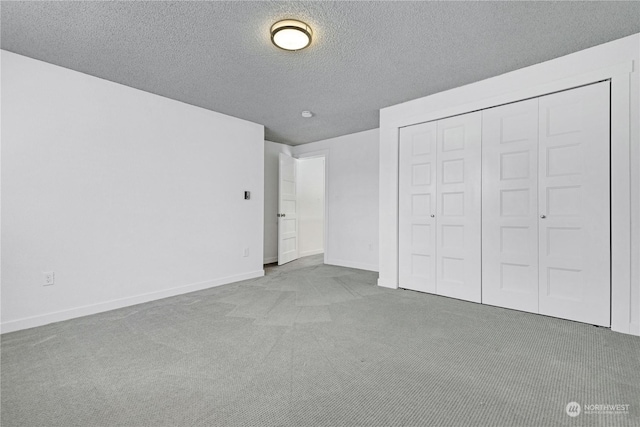 unfurnished bedroom with carpet, a closet, a textured ceiling, and baseboards