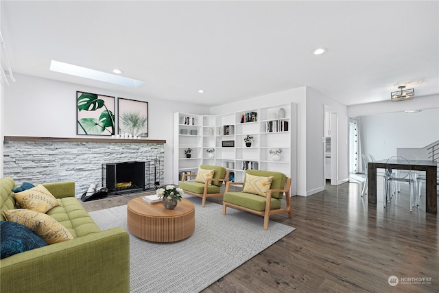 living room featuring dark hardwood / wood-style flooring, a stone fireplace, and a skylight