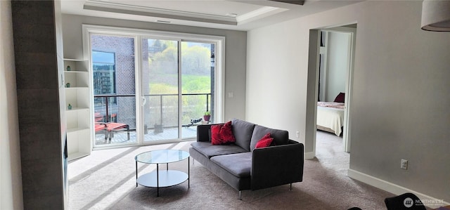 carpeted living area with crown molding and baseboards