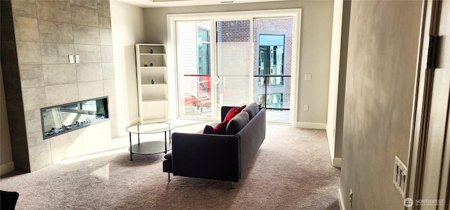 carpeted living area featuring visible vents, a fireplace, and baseboards