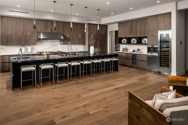 3263 Evergreen Point Rd, Medina, WA 98039 - kitchen with under cabinet range hood, wine cooler, a kitchen bar, modern cabinets, and recessed lighting